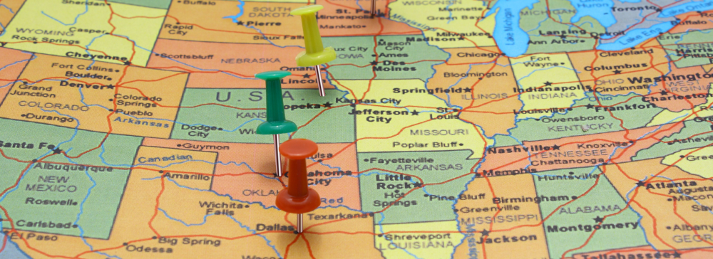 A road map of the United States with push pins marking cities
