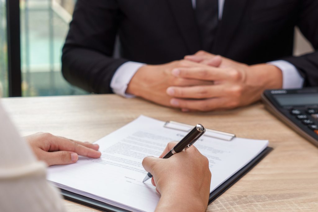 Woman signing contract or loan agreement document with businessman waiting for