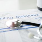 Health care billing statement with stethoscope, bottle of medicine for doctor's work in medical center stone background.