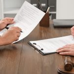 Law and justice. Lawyers working with documents at wooden table in office, closeup