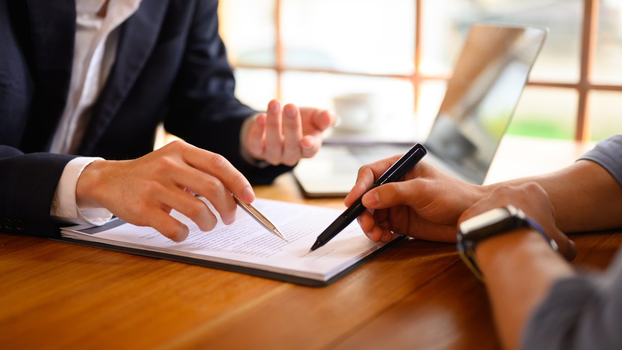 Closeup lawyer or insurance agent pointing at contract showing male client where to signature sign.