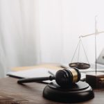 Business and lawyers discussing contract papers with brass scale on desk in office. Law, legal services, advice, justice and law concept picture with film grain effect