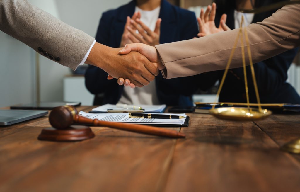 Middle age partner lawyers attorneys shaking hands after discussing a contract agreement done.