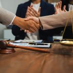 Middle age partner lawyers attorneys shaking hands after discussing a contract agreement done.